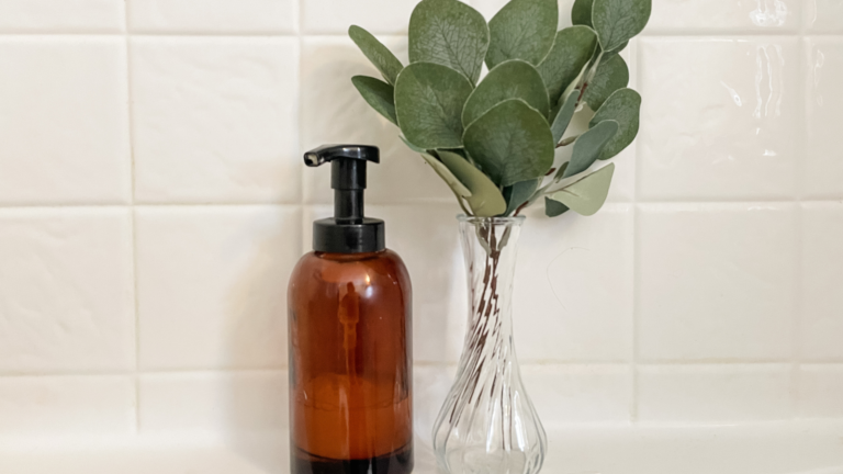 amber jar of soap and green stems in a jar