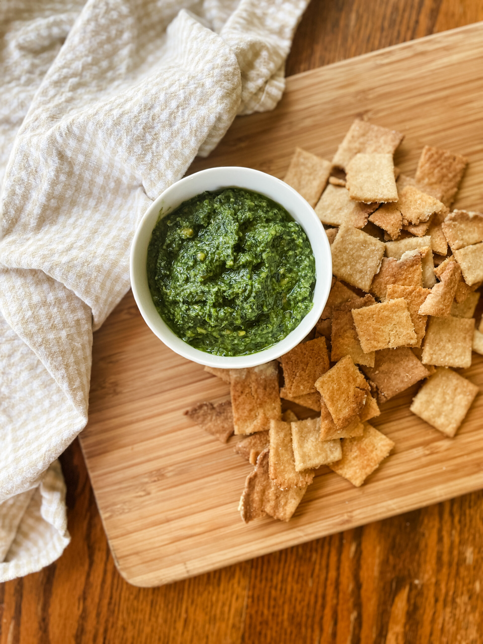crackers and basil pesto on a cutting board