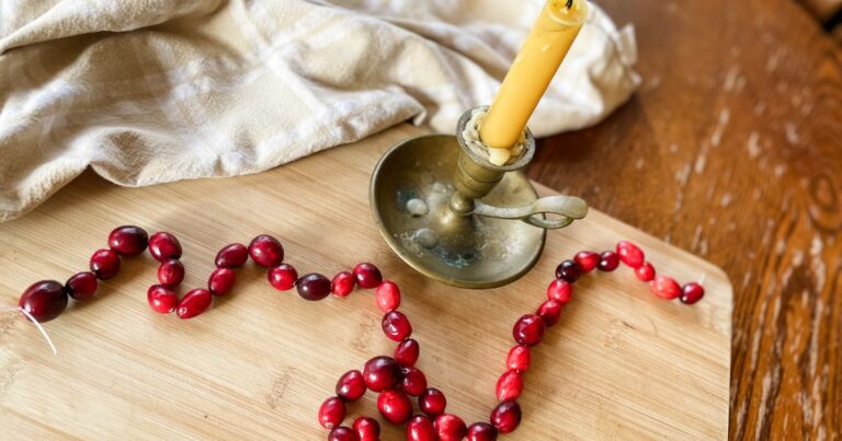 cranberry garland and candle on a wooden board
